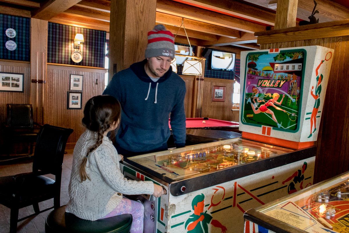 Family playing in the Retro Game Room with old fashioned pinball at Woodstock Inn and Resort in Woodstock Vermont