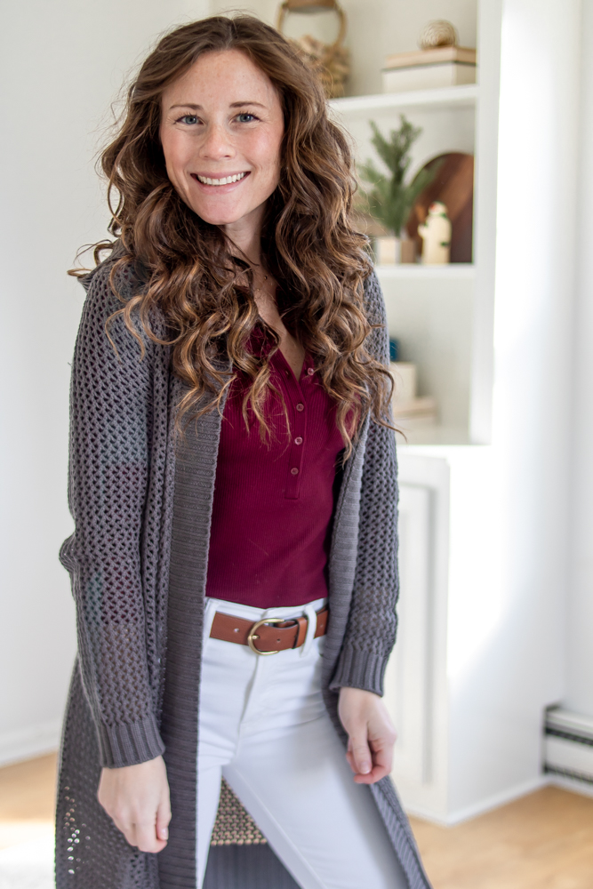 girl smiling wearing hooded grey sweater over a maroon shirt
