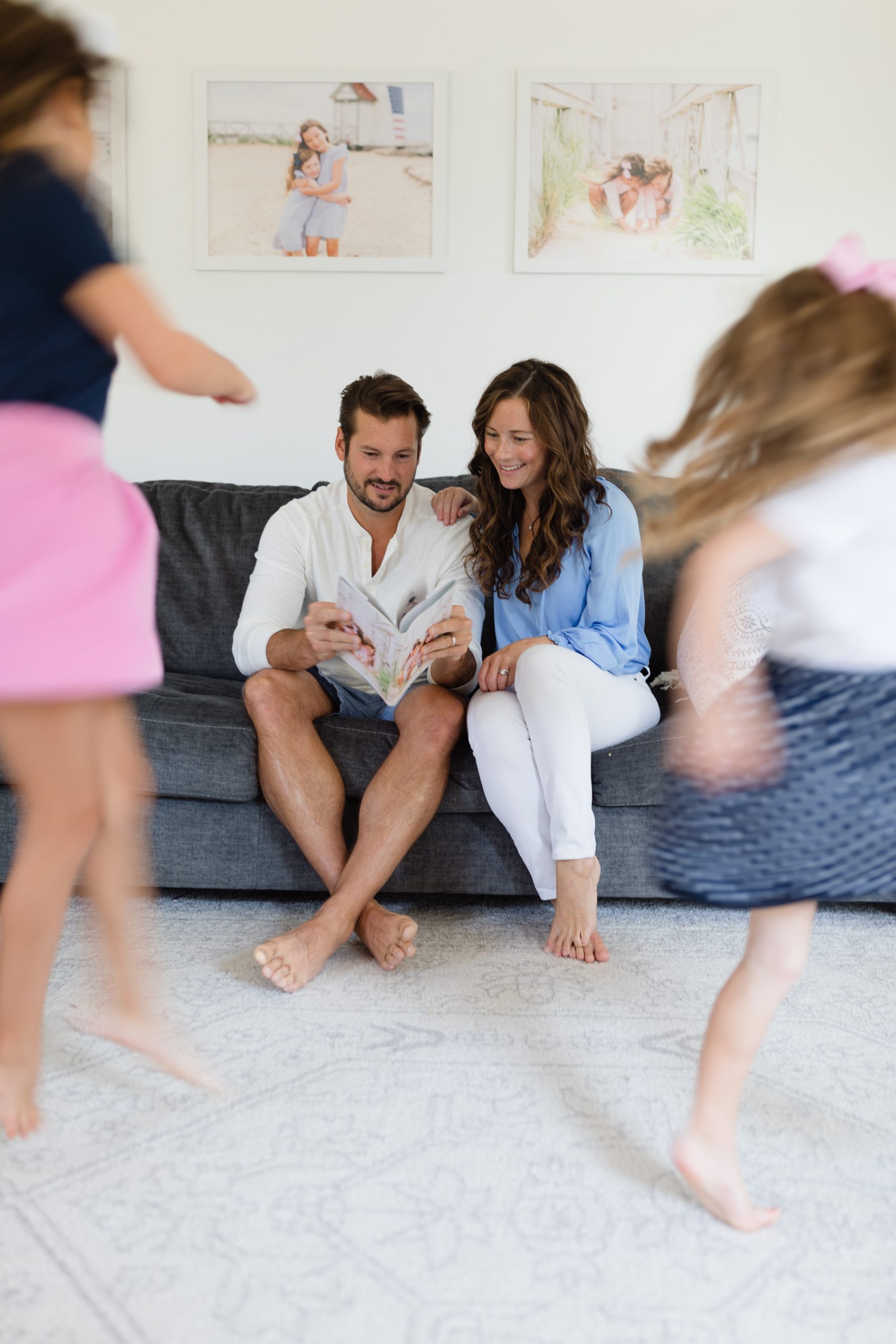 Mom and Dad looking at photo album from Artifact Uprising with children twirl in front of them